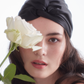 Model wearing White Trousseau 100% Pure Mulberry Silk hair Turban in Black and holding flowers