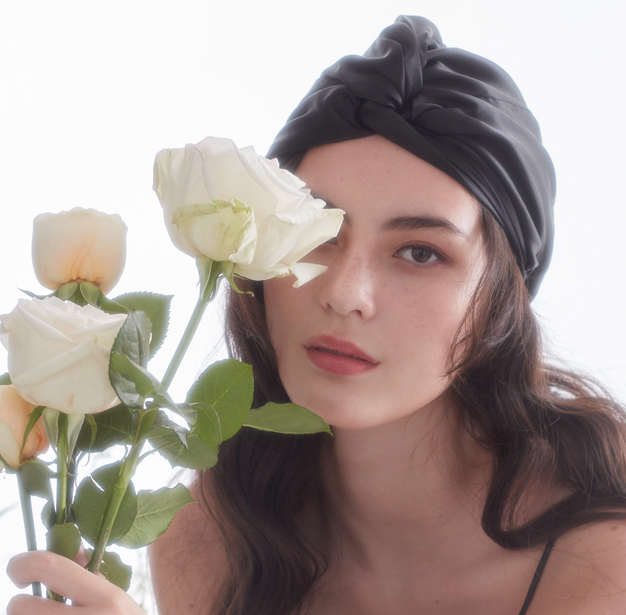 Model wearing White Trousseau 100% Pure Mulberry Silk hair Turban in Black and holding flowers
